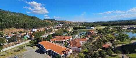 A large building with a red-tiled roof, surrounded by parking, greenery, and a lake.