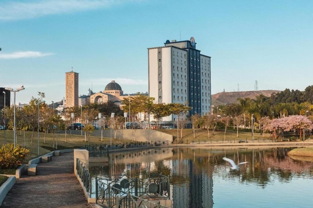 A park with a pond, a building with a dome, and a tall tower.