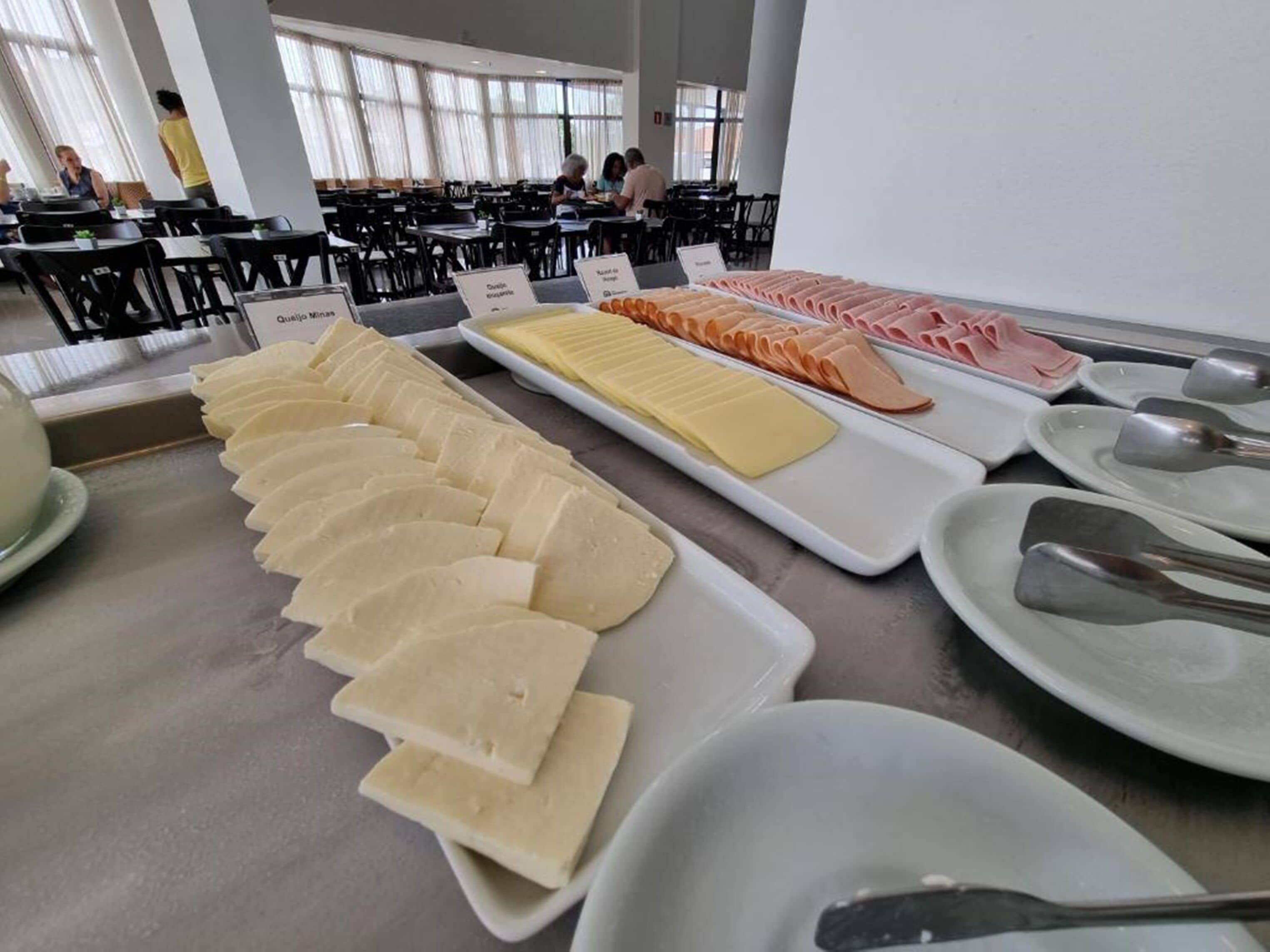 Buffet com diversos alimentos, incluindo queijo, presunto e outras charcutarias.