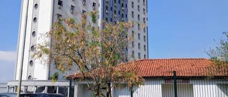 Un edificio de varios pisos con techo plano y una estructura más pequeña con tejado de tejas rojas al frente.