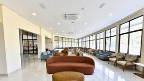 Un vestíbulo amplio con un sofá curvo grande, varios sillones y un otoman redondo.