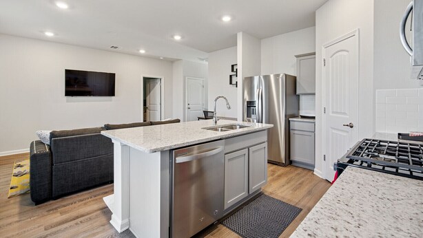 A modern kitchen with a central island, stainless steel appliances, and a built-in oven. - Charming Retreat 30 Minutes from Vibrant New Orleans - Ideal Short-Term Rental! (Slidell)