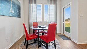 A dining area with a round table and four red chairs, large windows with blinds, and a view of the outdoors. - Charming Retreat 30 Minutes from Vibrant New Orleans - Ideal Short-Term Rental! (Slidell)