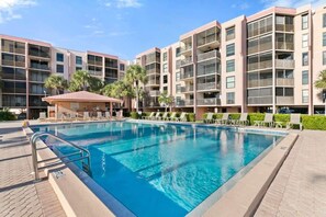 Una piscina con lettini e un edificio con balconi.