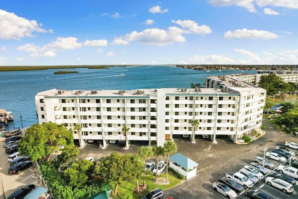 A multi-story hotel with a parking lot and a view of a large body of water.