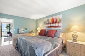 Una camera da letto con un letto, comodini, un quadro e vista attraverso una porta vetrata.