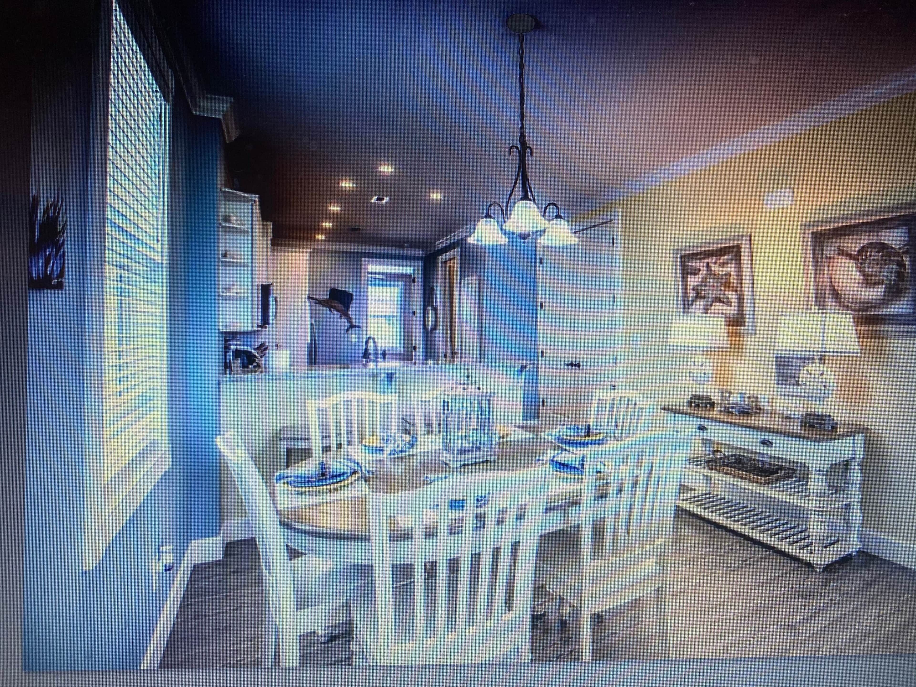 A modern dining area with a central table, chairs, and a chandelier.