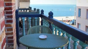 A balcony with two green metal tables and chairs, overlooking a beach with a clear view of the sea. - Le 8 ∙ Cosy apartment with sea-view balcony (Mers-les-Bains)