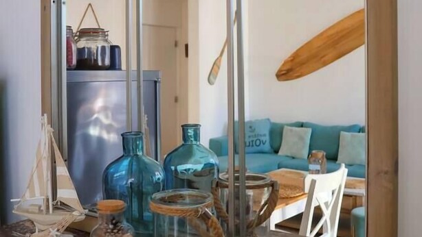 A kitchen counter with a large mirror reflecting a dining area, a refrigerator, and a wooden ceiling beam. - Le 8 ∙ Cosy apartment with sea-view balcony (Mers-les-Bains)