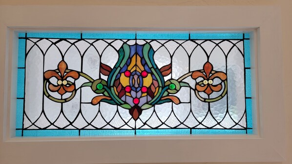 A stained glass window with a symmetrical floral design. - One Block Walk to Old Town - Historical Bungalow (Cottonwood)