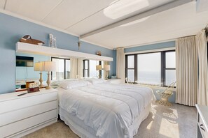 Relax in a spacious room with a large bed, console, and wicker chair.
