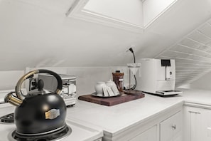 A modern kitchen with a kettle, a coffee maker, and a toaster on the countertop.