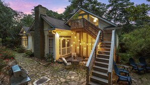 A cozy cabin with a stone patio, outdoor seating, and a staircase leading to a deck.