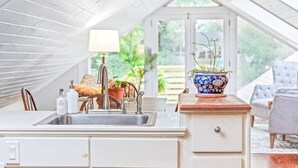 A modern kitchen with a white countertop, a sink, and a potted plant.