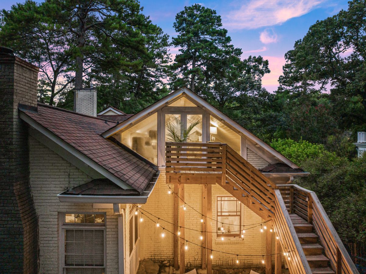 A two-story house with a wooden deck and a staircase leading to a balcony.