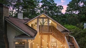 A two-story house with a wooden deck and a staircase leading to a balcony.