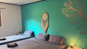 Ein Zimmer mit zwei Betten, einem Wandbild und einem Nachttisch mit Lampe.