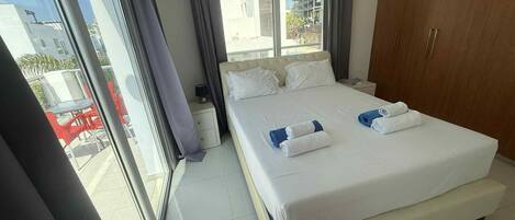 Een hotelkamer met een groot bed, een nachtkastje, een kledingkast en een raam met gordijnen.