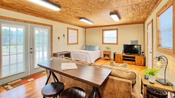 A cozy room with a bed, a TV, a dining table, and a sofa.