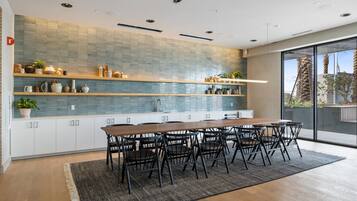Una cocina moderna con una mesa y sillas de madera, un salpicadero de azulejos y un amplio ventanal con vistas a palmeras.