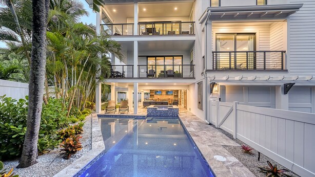 Una casa moderna de varios pisos con un patio central, piscina y jardín bien cuidado.