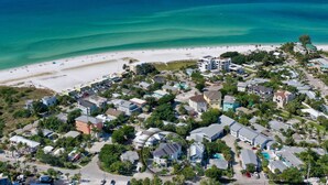 Vista aérea de una zona residencial costera con casas, una playa y un océano azul y despejado.