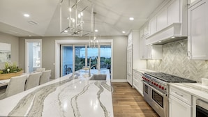 Una cocina moderna con una isla grande, electrodomésticos de acero inoxidable y vistas al exterior.