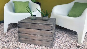 A room with two white chairs, each with a green pillow, a wooden coffee table with two potted plants, and a yellow wall. - Matua: Spacious `loft style` studio with pool (Willemstad)
