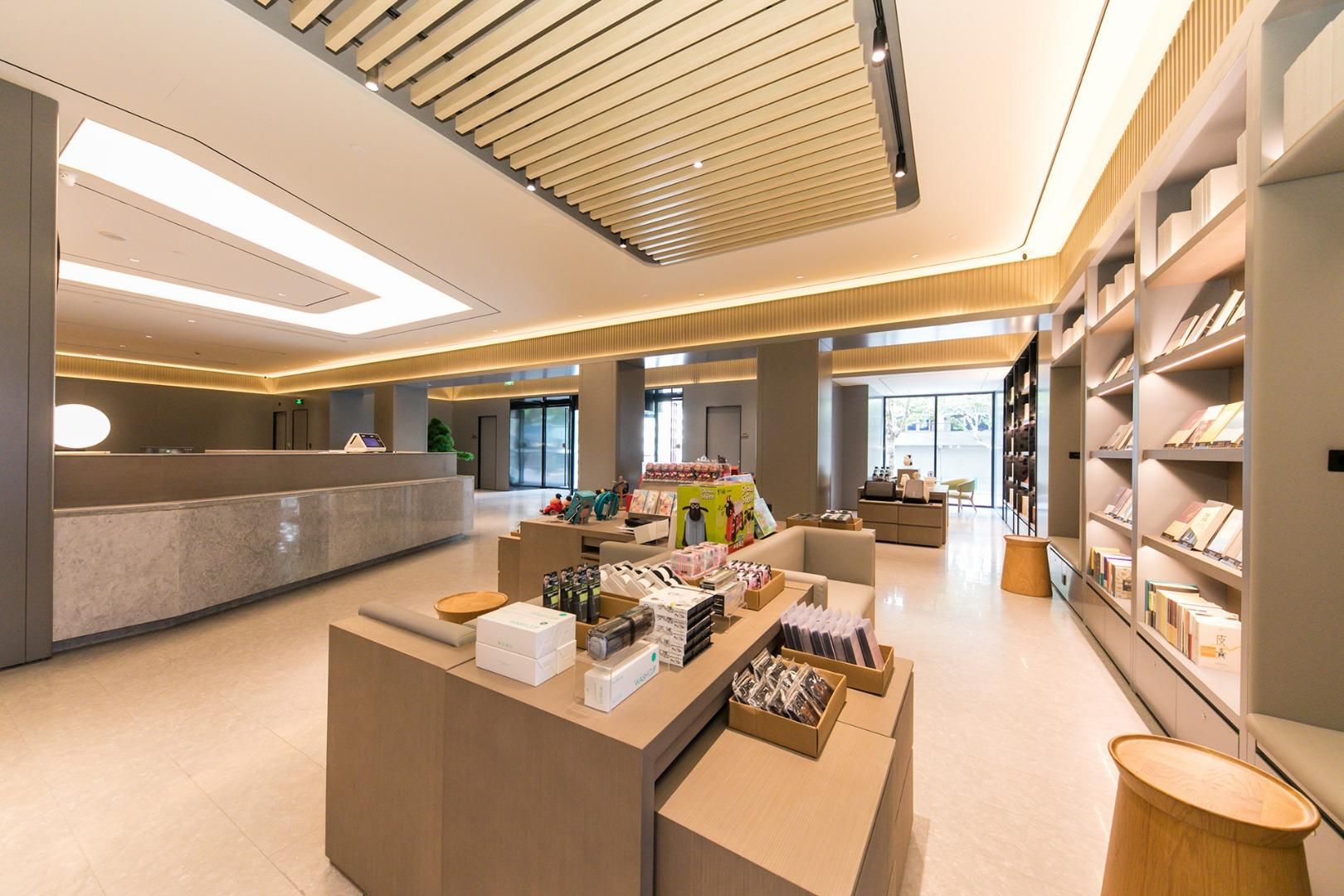 A modern hotel lobby with a reception desk, seating area, and bookshelves.