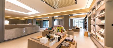 A modern hotel lobby with a reception desk, seating area, and bookshelves.