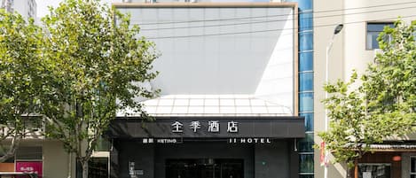 A hotel entrance with a modern facade, a large glass window, and a sign reading 'JI HOTEL'.