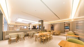 A modern interior with multiple seating areas, including tables and chairs, and a counter with a display.