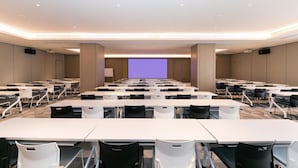 A conference room with multiple tables and chairs, a large screen, and a projector. - Ji Hotel Wuxi Railway Station Branch (Wuxi)
