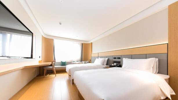 A hotel room with two beds, a desk, a chair, a window, and a bedside table. - Ji Hotel Wuxi Railway Station Branch (Wuxi)