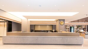 A modern hotel lobby with a reception desk, a coffee station, and a bookstore. - Ji Hotel Wuxi Railway Station Branch (Wuxi)