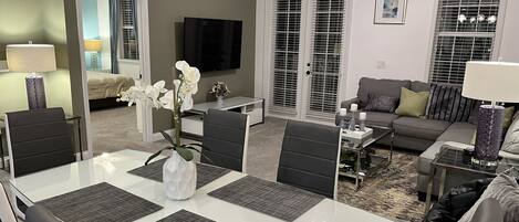A modern living room with a dining area, a sofa, and a television.