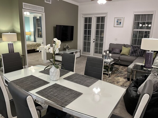 A modern living room with a dining area, a sofa, and a television.