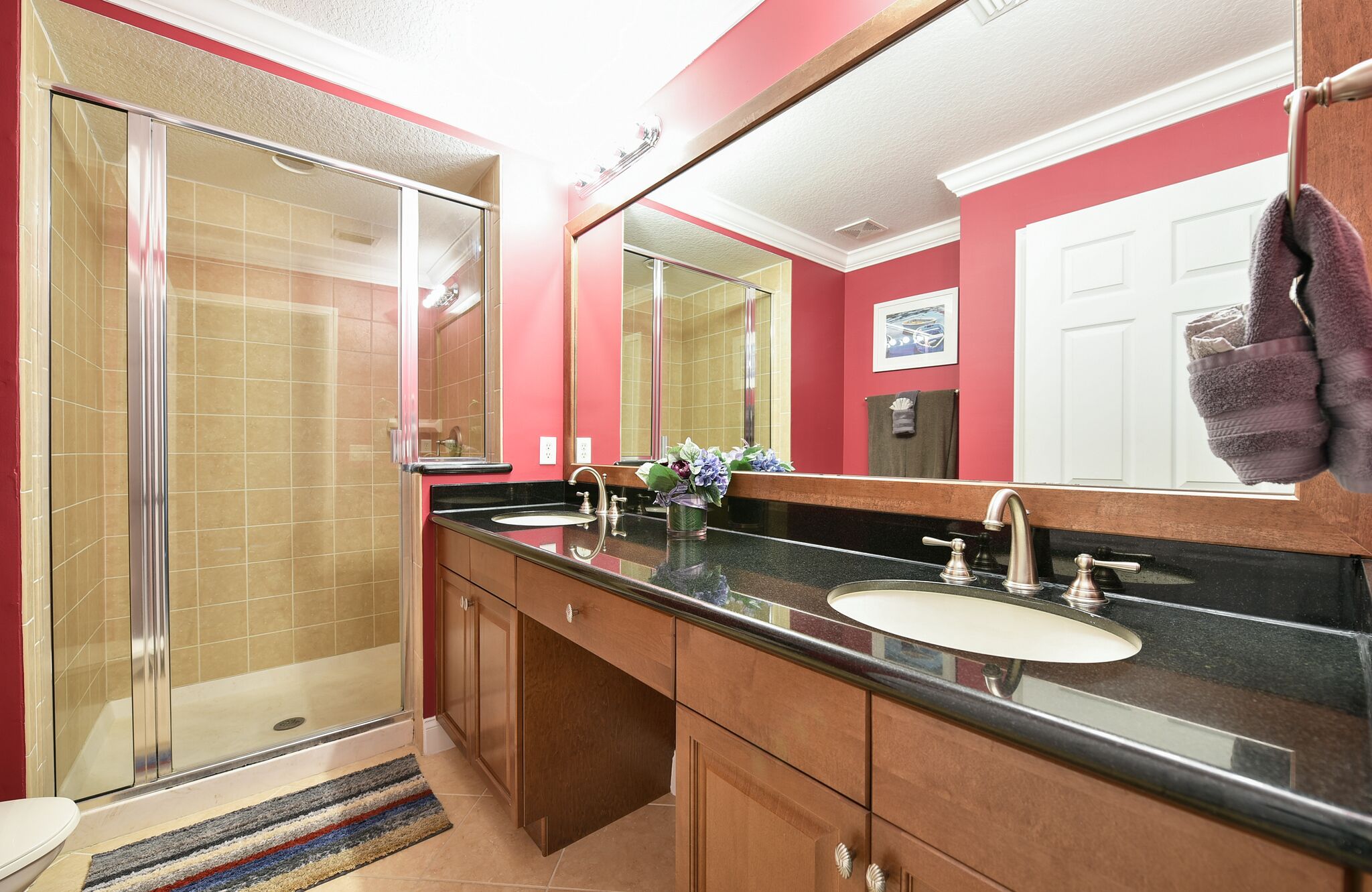 Un baño con cabina de ducha de vidrio, lavamanos doble y un espejo grande.