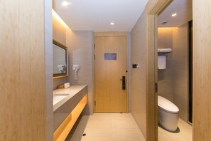 A modern bathroom with a wooden door, a sink, a mirror, and a toilet. - Ji Hotel (Shanghai)