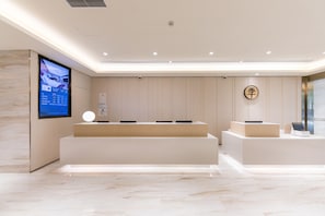 A modern reception desk with a digital screen, a wooden panel wall, and a clean, minimalist design. - Ji Hotel (Shanghai)