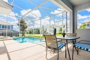 A covered outdoor area with a pool, chairs, and a table. - Modern 5BR/5BA Vacation Home with Private Pool CG1593 (Davenport)