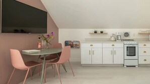 A modern kitchen with white cabinets, a built-in oven, and a dining area with a table and chairs.