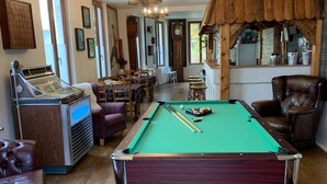 Una mesa de billar en una habitación con suelo de madera, una mesa de pool, una máquina de billar y un soporte para tacos de billar.