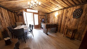 Una habitación rústica de madera con dardos, una mesa de fútbol de mesa y un televisor.