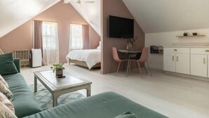 Ein Schlafzimmer im Loft-Stil mit Bett, Schreibtisch und Stuhl. An der Wand ist ein Fernseher angebracht und es gibt ein Fenster mit Vorhängen.