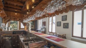 Un restaurante con una barra larga, techo de madera y amplios ventanales.
