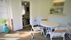 A dining area with a round table and white chairs, a potted plant, and a window with a view. - 2 bed/2 Ba Venice Island Villa - Walk to Beach & Historic Downtown Venice! (Venice)