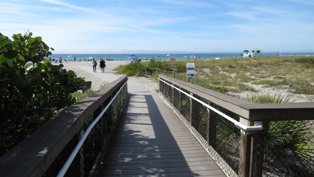 A wooden boardwalk leading to a beach with people walking and sitting. - 2 bed/2 Ba Venice Island Villa - Walk to Beach & Historic Downtown Venice! (Venice)