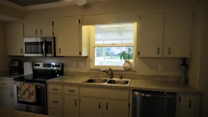 A kitchen with stainless steel appliances, a double sink, and a window providing natural light. - 2 bed/2 Ba Venice Island Villa - Walk to Beach & Historic Downtown Venice! (Venice)