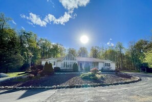 Ein Haus mit Veranda, Auffahrt und einem angelegten Garten mit Steinrand.